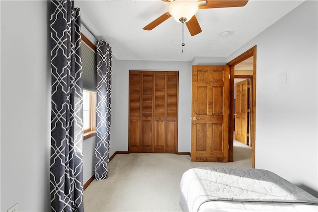 carpeted bedroom with a closet, ceiling fan, and baseboards