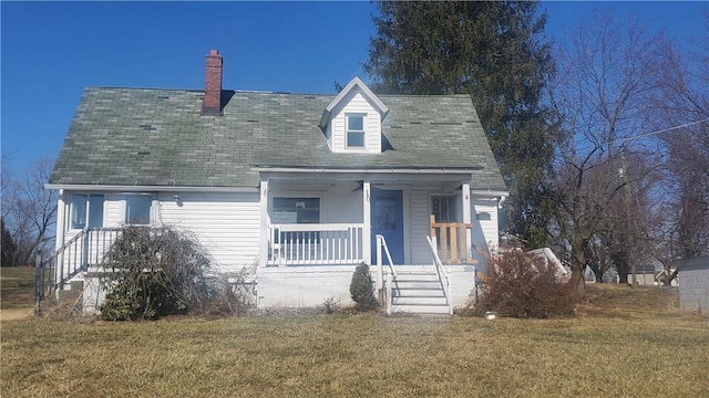 new england style home featuring a porch, a front yard, and a chimney