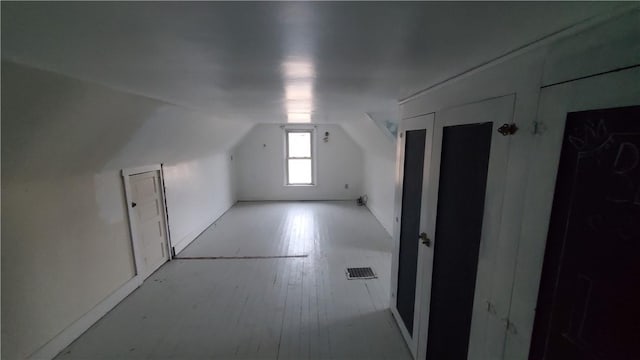 additional living space featuring visible vents, lofted ceiling, and hardwood / wood-style flooring