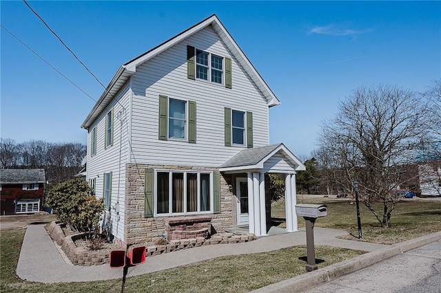 traditional-style house featuring stone siding and a front yard