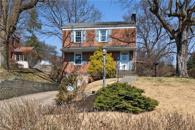 view of front facade with a front lawn, brick siding, and a chimney