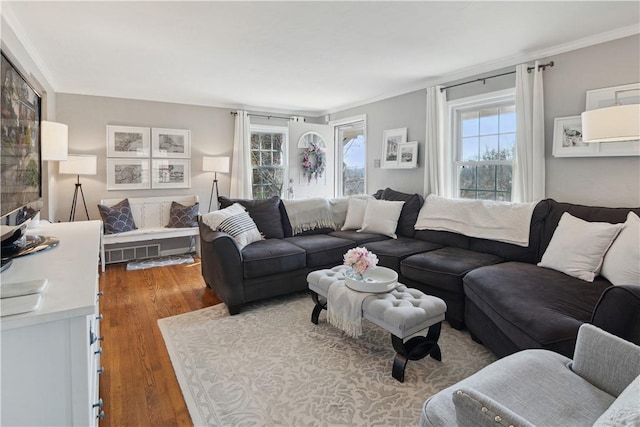 living area featuring visible vents, wood finished floors, and ornamental molding