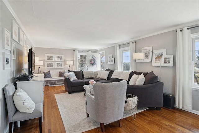 living room with wood finished floors, visible vents, and ornamental molding