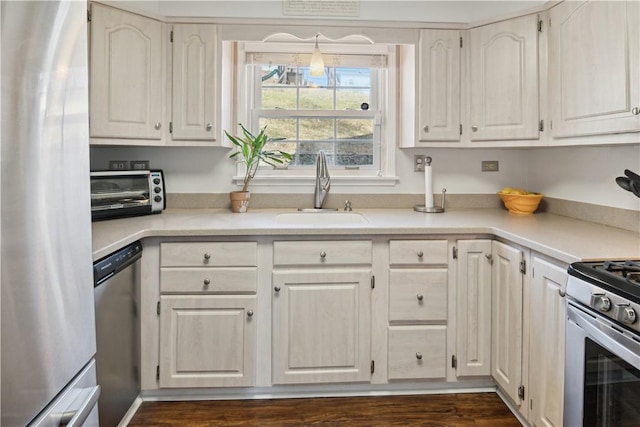 kitchen featuring a toaster, light countertops, white cabinets, stainless steel appliances, and a sink