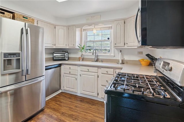 kitchen featuring a sink, light countertops, dark wood finished floors, and stainless steel appliances