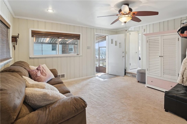 carpeted living room featuring ceiling fan, visible vents, and ornamental molding