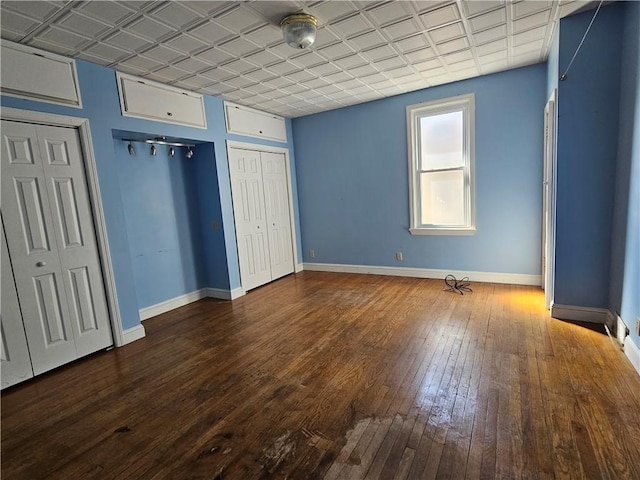 unfurnished bedroom featuring an ornate ceiling, baseboards, and dark wood finished floors