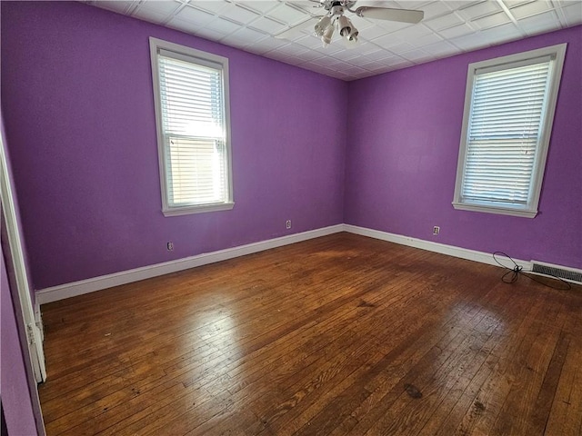 unfurnished room with visible vents, baseboards, dark wood-type flooring, and a ceiling fan