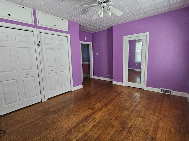 unfurnished bedroom featuring hardwood / wood-style floors, baseboards, visible vents, and an ornate ceiling