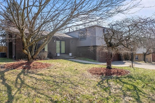 split level home featuring a front yard, fence, brick siding, and driveway