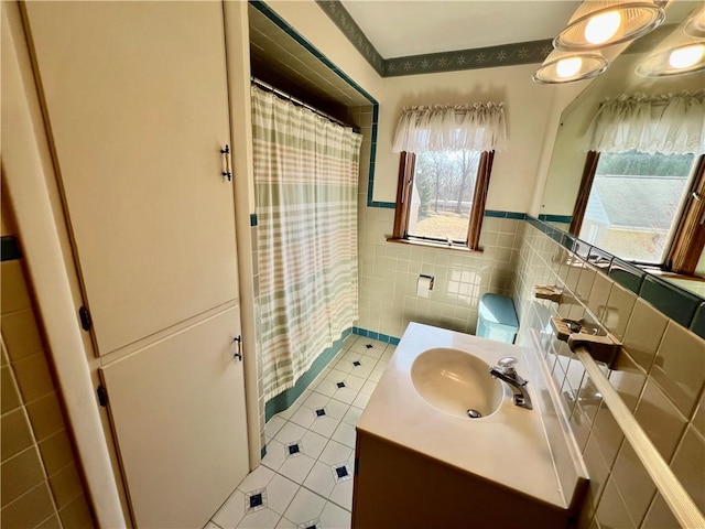 full bathroom featuring tile patterned floors, a wainscoted wall, a shower with curtain, tile walls, and vanity