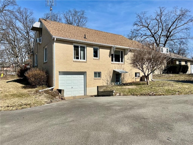 exterior space with a garage, brick siding, driveway, and a shingled roof