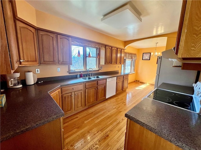 kitchen featuring electric range, brown cabinets, a sink, light wood-style floors, and dishwasher