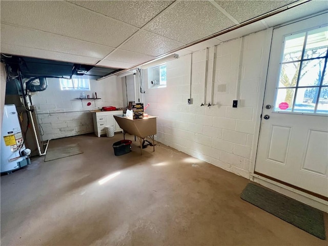 below grade area with a drop ceiling, concrete block wall, and a sink