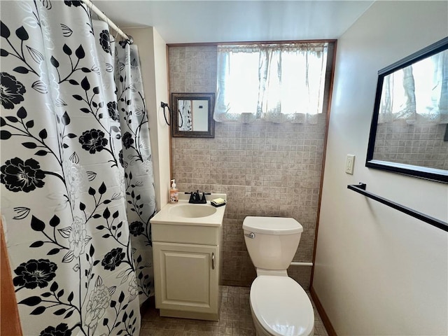 full bath featuring a shower with shower curtain, toilet, tile walls, and vanity