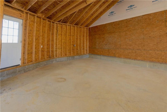 spare room featuring lofted ceiling and concrete flooring