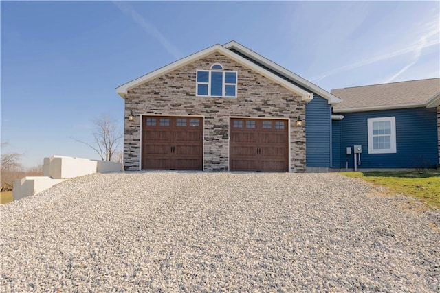 view of front of home featuring a garage, stone siding, and driveway