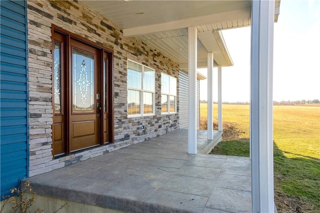 entrance to property with a lawn, covered porch, and stone siding