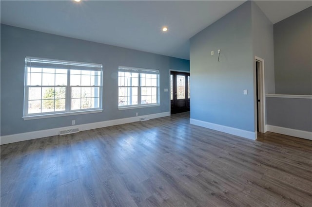 empty room with visible vents, plenty of natural light, baseboards, and dark wood-style floors