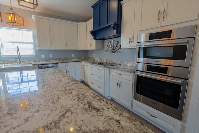 kitchen featuring light stone countertops, under cabinet range hood, stainless steel appliances, white cabinetry, and a sink