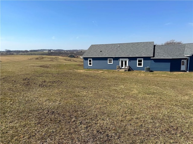 back of property featuring a lawn, entry steps, and a shingled roof