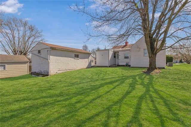 back of house featuring a lawn and an outdoor structure