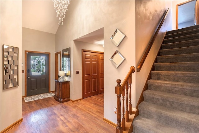 entryway featuring stairway, wood finished floors, baseboards, and high vaulted ceiling