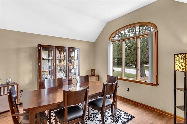 dining space with vaulted ceiling, light wood-style flooring, and baseboards