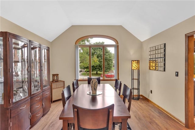 dining area featuring light wood finished floors, baseboards, and lofted ceiling