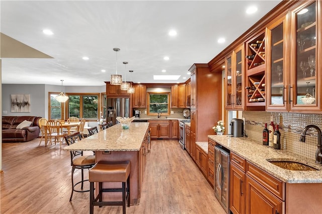 kitchen featuring a sink, a kitchen bar, appliances with stainless steel finishes, and brown cabinetry