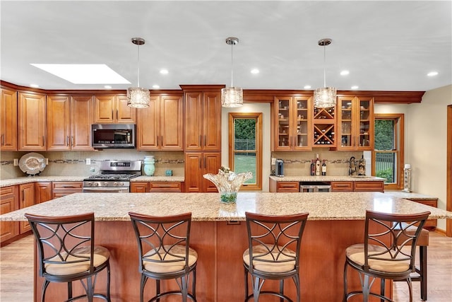 kitchen with decorative backsplash, light wood-style flooring, appliances with stainless steel finishes, and a center island