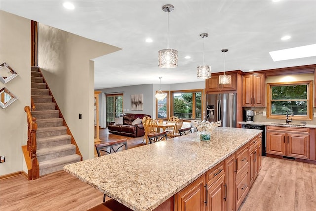 kitchen with a center island, dishwasher, light wood-type flooring, stainless steel refrigerator with ice dispenser, and a sink