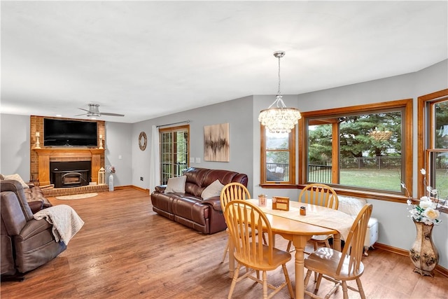 dining room featuring baseboards, a brick fireplace, and light wood finished floors