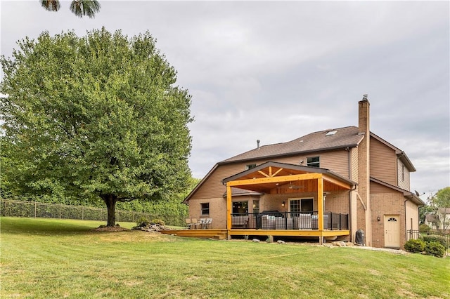 rear view of property with a yard, brick siding, a deck, and fence