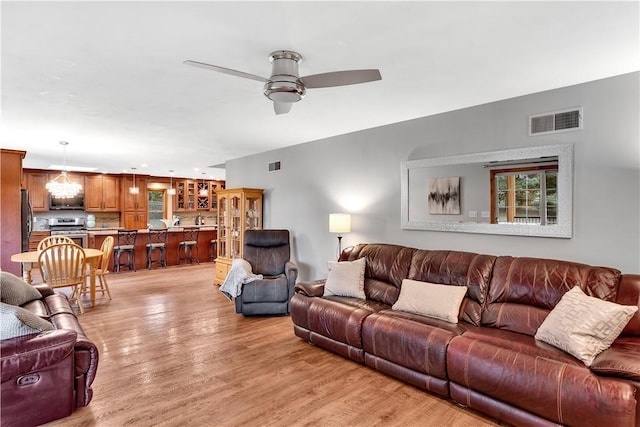 living area with light wood-style floors, visible vents, and ceiling fan