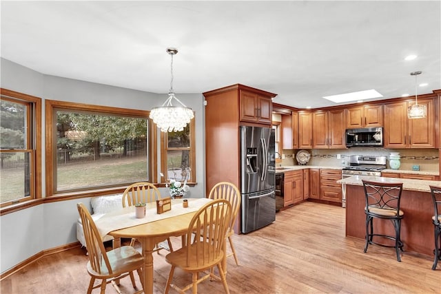 kitchen with stainless steel appliances, backsplash, a notable chandelier, and light wood finished floors