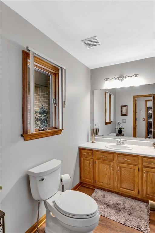 bathroom with visible vents, baseboards, toilet, and vanity