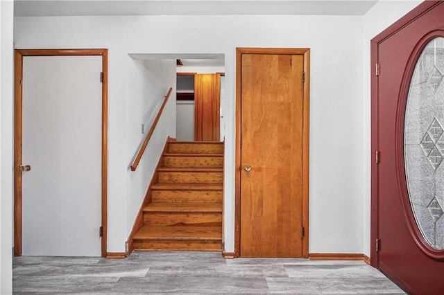 foyer with baseboards, wood finished floors, and stairs