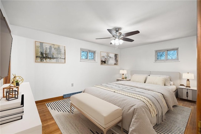 bedroom featuring multiple windows, baseboards, a ceiling fan, and light wood finished floors