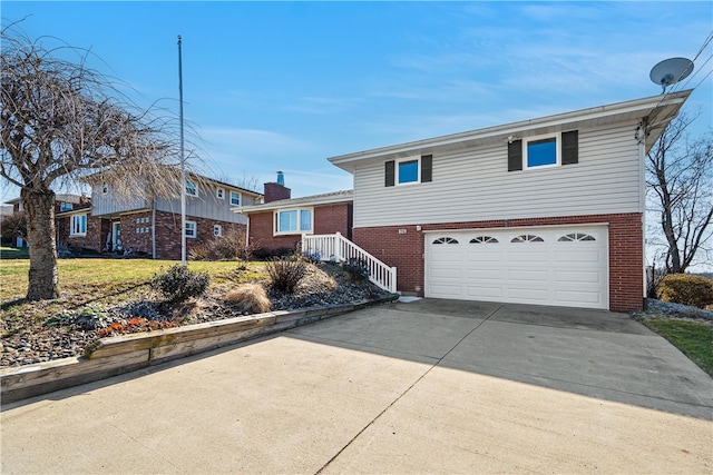 split level home with a front lawn, driveway, a garage, brick siding, and a chimney