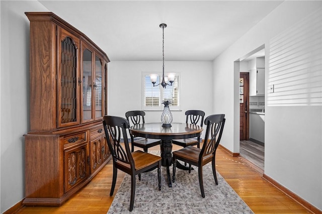 dining area with baseboards, light wood finished floors, and a chandelier