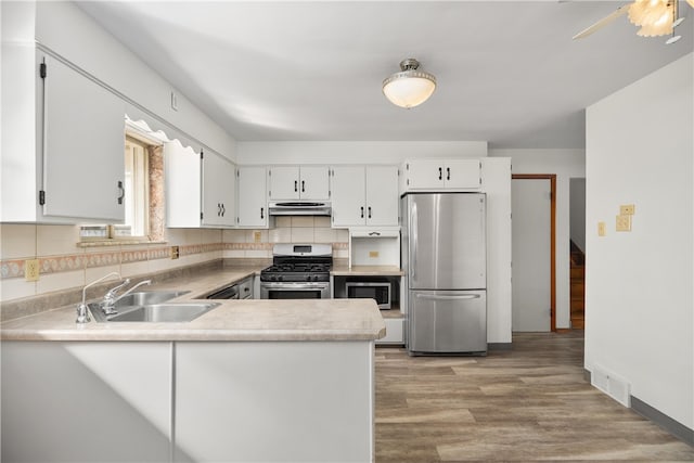 kitchen with visible vents, light wood-style flooring, a sink, under cabinet range hood, and appliances with stainless steel finishes