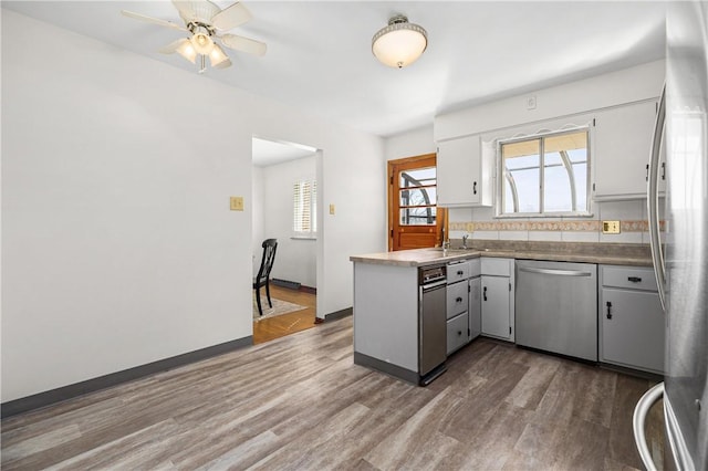 kitchen featuring dark wood-style floors, a peninsula, stainless steel appliances, and a ceiling fan