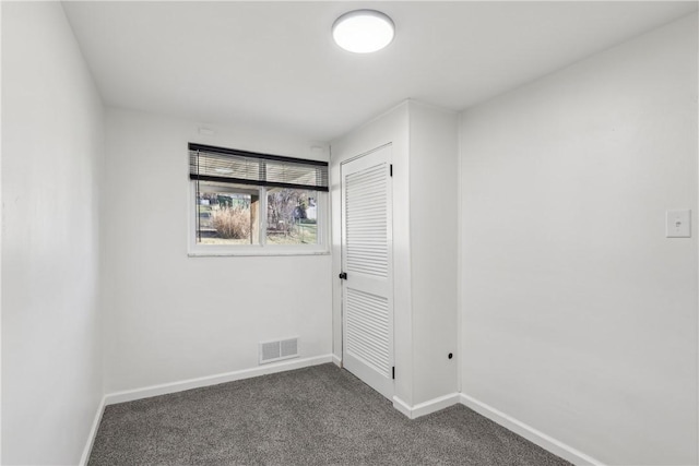 unfurnished room with baseboards, visible vents, and dark carpet