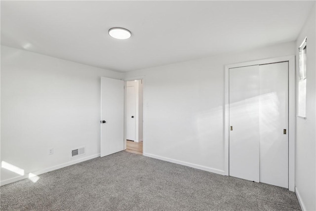 unfurnished bedroom featuring carpet flooring, baseboards, visible vents, and a closet