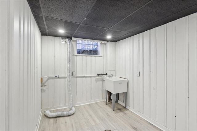 basement featuring a paneled ceiling and wood finished floors