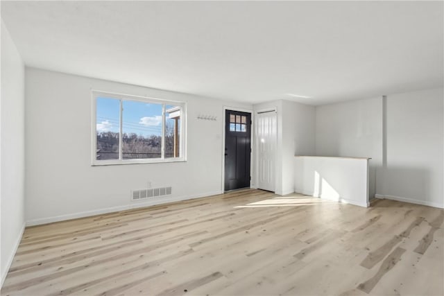 unfurnished living room with visible vents, baseboards, and wood finished floors