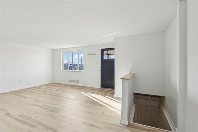 unfurnished living room featuring visible vents, baseboards, and wood finished floors