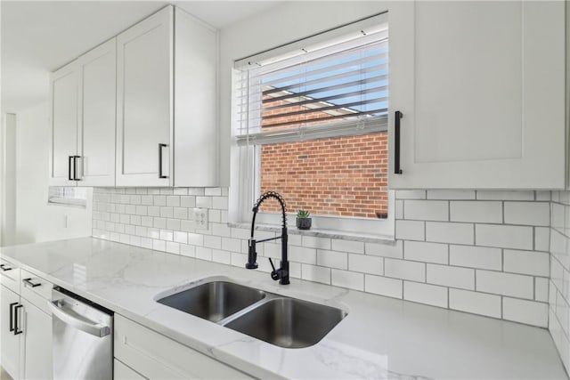 kitchen featuring light stone counters, white cabinetry, a sink, dishwasher, and backsplash