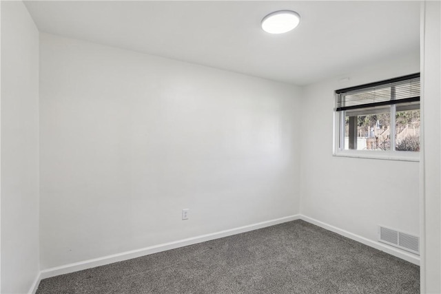 spare room with baseboards, visible vents, and dark colored carpet